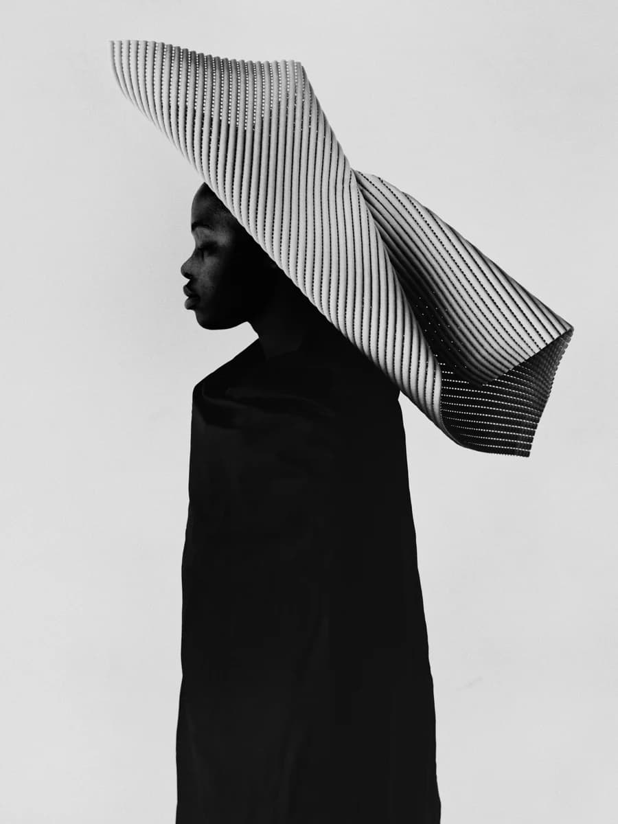 Profile portrait wearing a sculptural striped headpiece. From Champions by Bastiaan Woudt.
